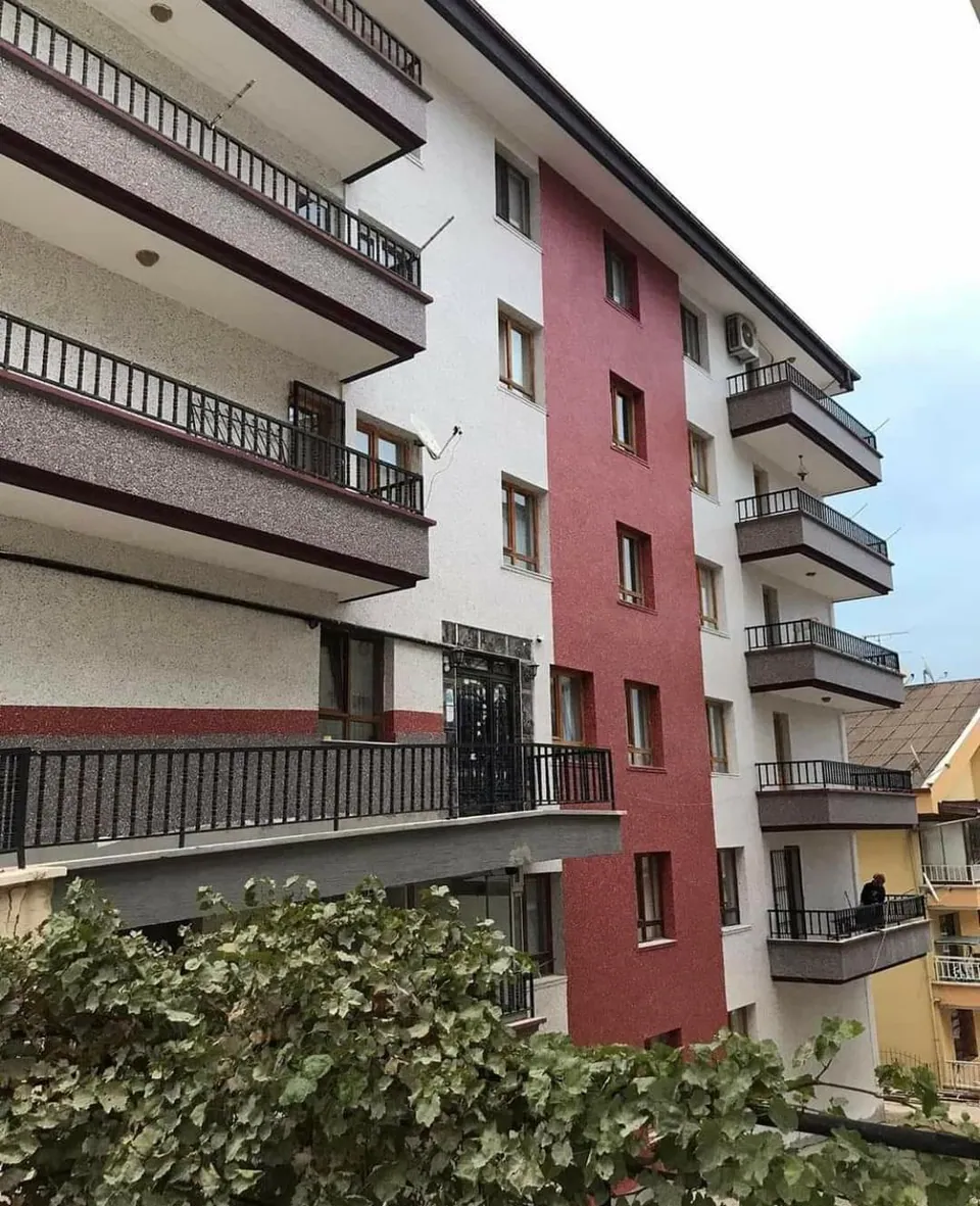 Kırmızı ve bej dokulu kaplamalı balkonlu apartman cephesi
