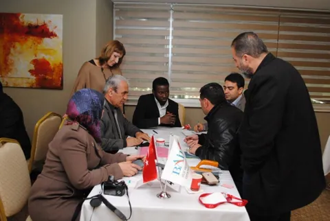 Toplantı masası etrafında görüşme yapan katılımcılar