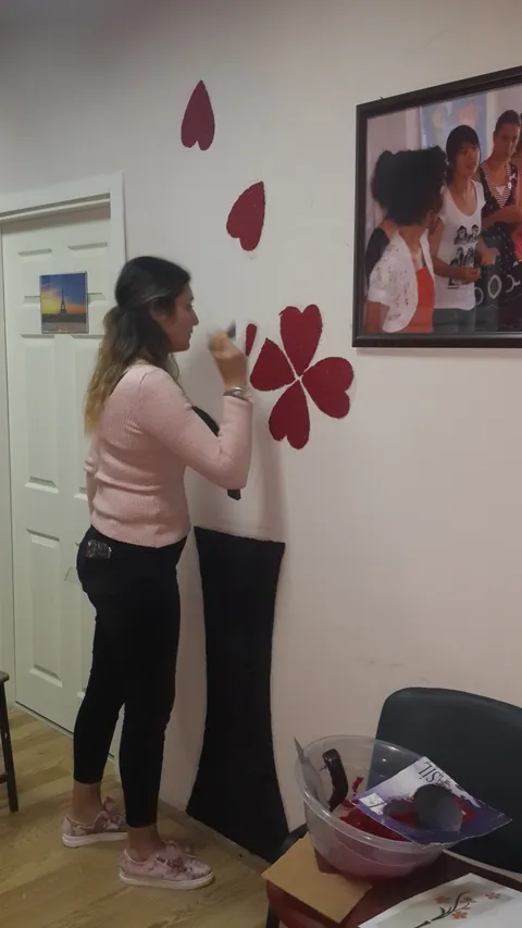 Ofis duvarına siyah vazo motifi üzerine kırmızı şekiller uygulayan uygulayıcı
