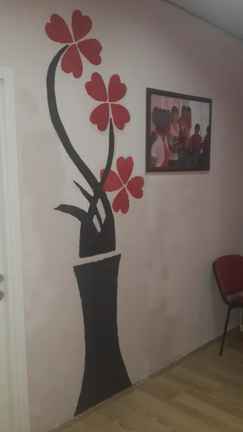 Beyaz duvarda siyah vazo ve kırmızı çiçek motifi