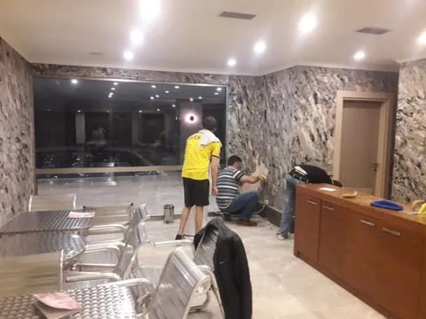 Spa salonunda siyah-beyaz mermer desenli pamuk sıva uygulayan iki usta